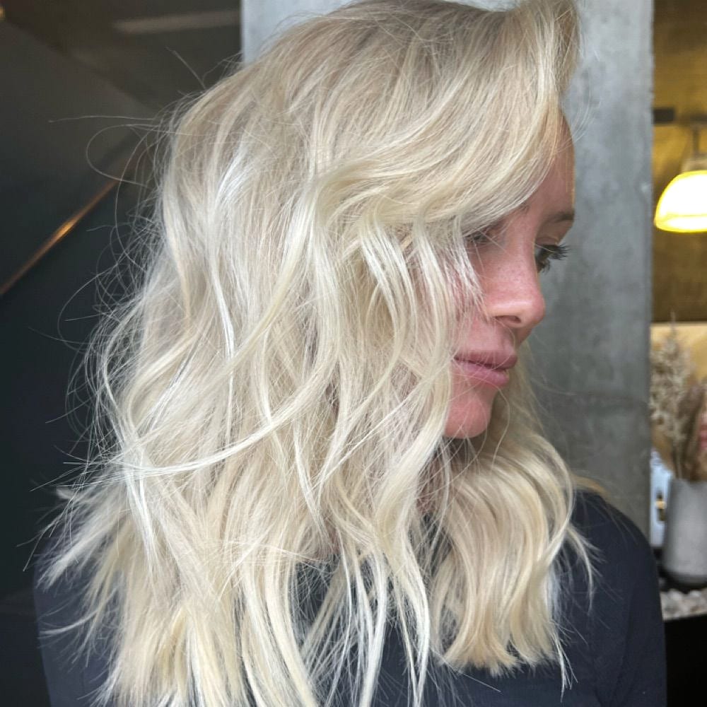 Side profile of a woman with wavy platinum blonde hair in the salon